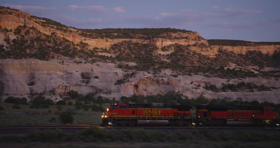 Cargo train traveling on the tracks next to the mountains at sunset