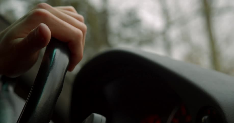 A mans hand on a steering wheel as he drives