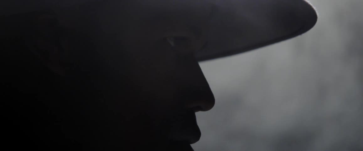 A man wearing a hat with smoke in the background