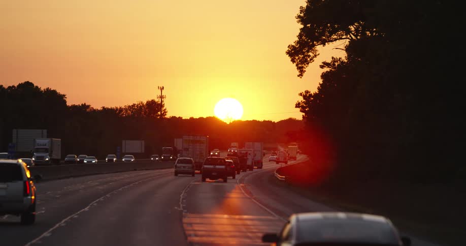 Sun setting on a red sky over the traffic in the highway