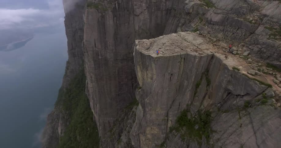 Two people stand on the edge of a mountain