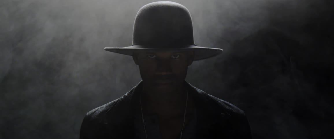 A young black man surrounded by smoke lifts his head up