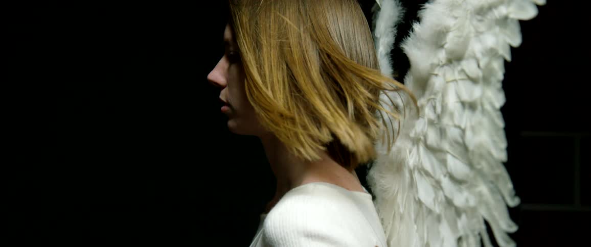 A gust of air blows a womans hair as she wears angel wings on her back