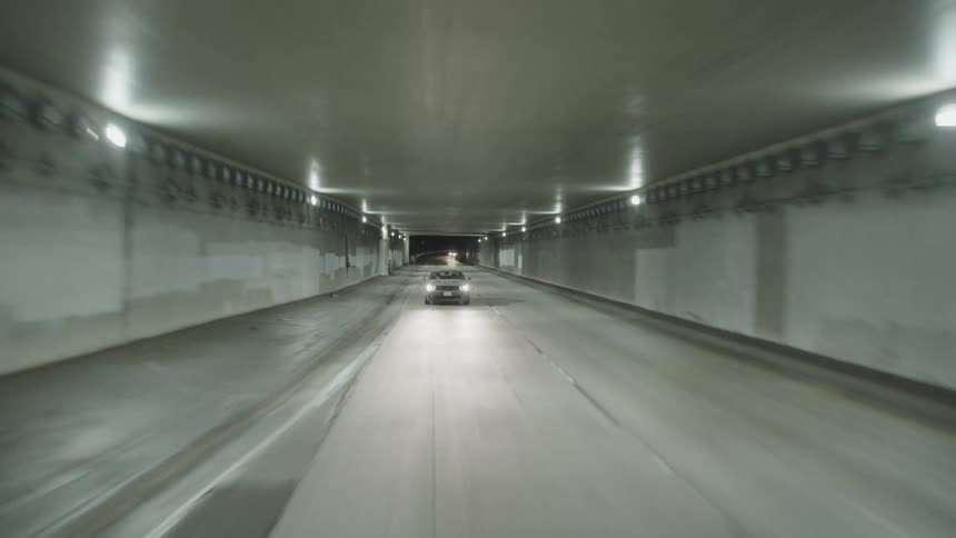 Twisting footage of a vehicle driving at full speed inside a tunnel at night