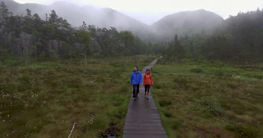 A man and woman hike on a wood-plank trail
