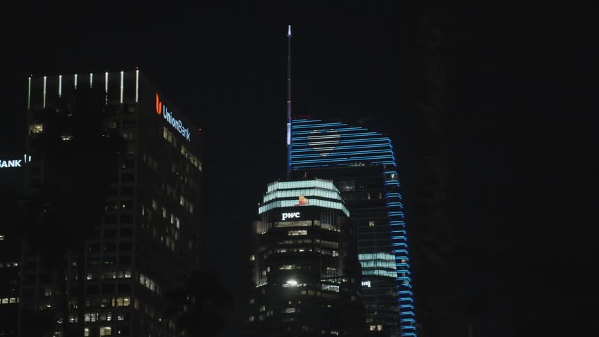 A city skyline with buildings and skyscrapers with trees in the foreground and the sky in the background