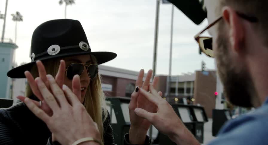 A man and woman touching hands with buildings the sky and clouds in the background