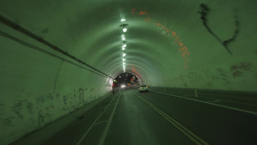 Lights and graffiti are revealed as a car drives through a tunnel