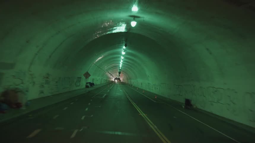 A green lit tunnel in a metro city at night