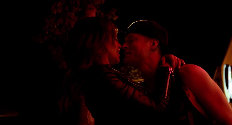 A man and woman are kissing outdoors at night