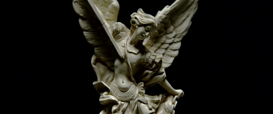 Statue of an angel carrying a sword against a black background