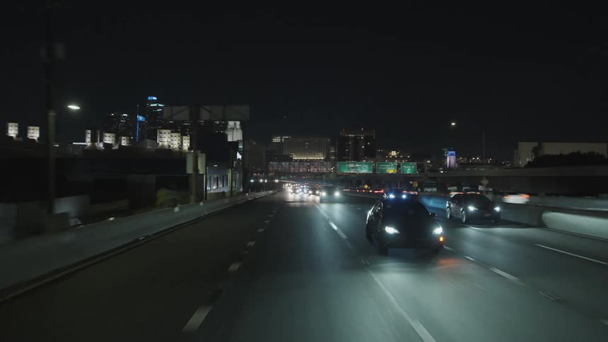Vehicle drives through a city highway at night