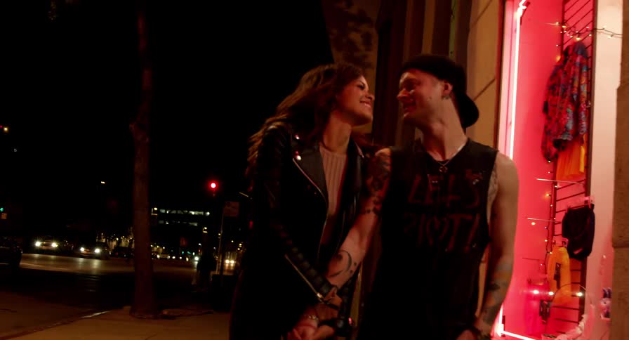 Young couple holding hands while walking on the city streets at night