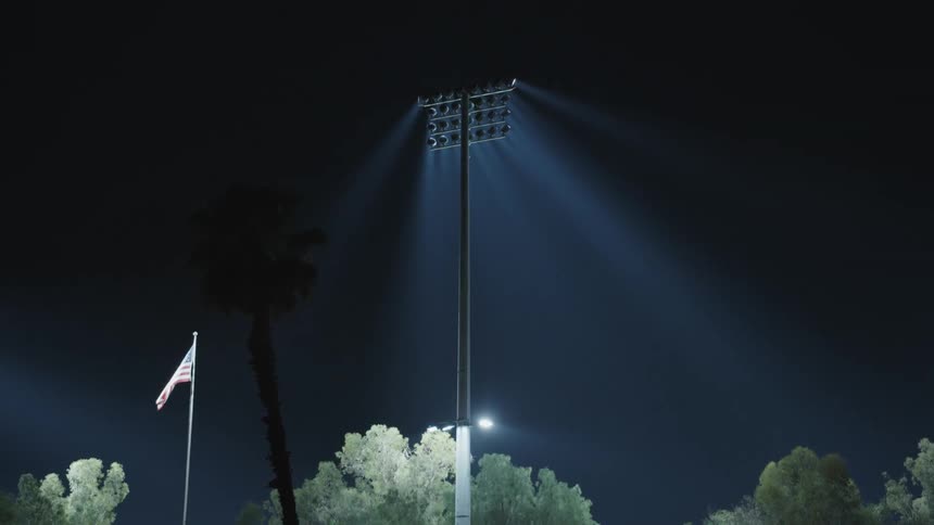 Stadium lights lit up while a flag blows in the air