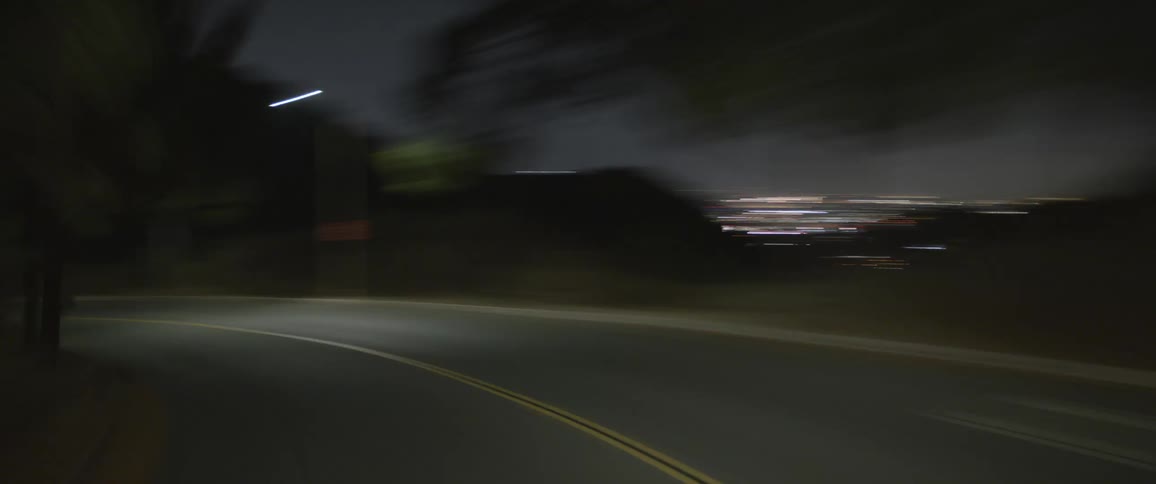A time lapse of a car driving down a street with the city skyline in the distance