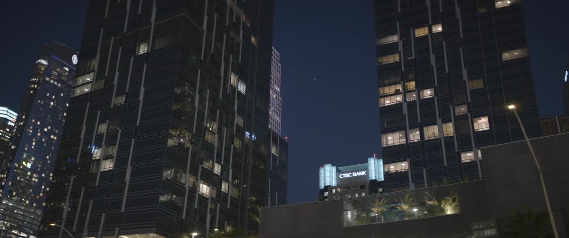 A nighttime view of buildings downtown with some lights through the windows