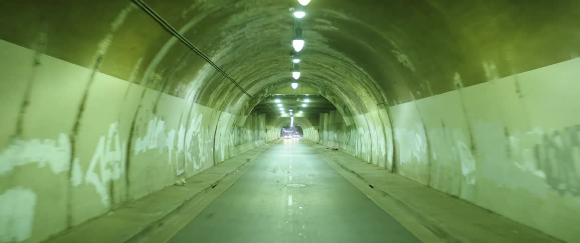 An interior of a tunnel with cement walls and a row of lights