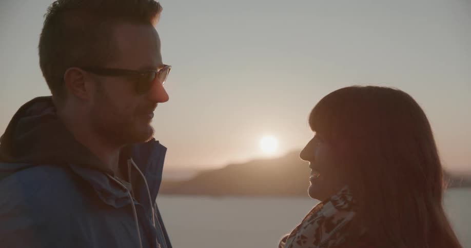 A man and women talk and laugh at sunset