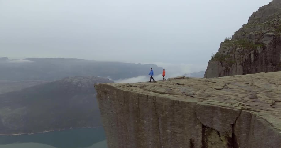 Two people walk up to a cliff edge