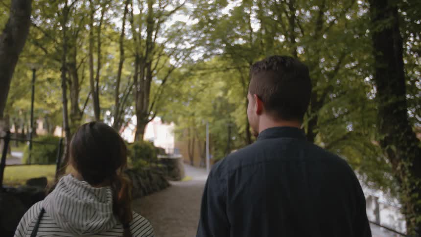 A man and women talk and walk along a cobblestone path