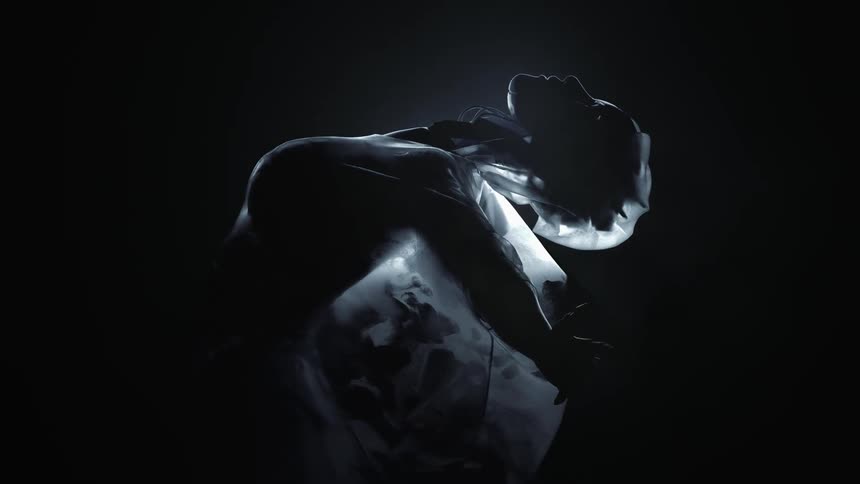 Light shines through the sheer dress of a dancer as she leans back