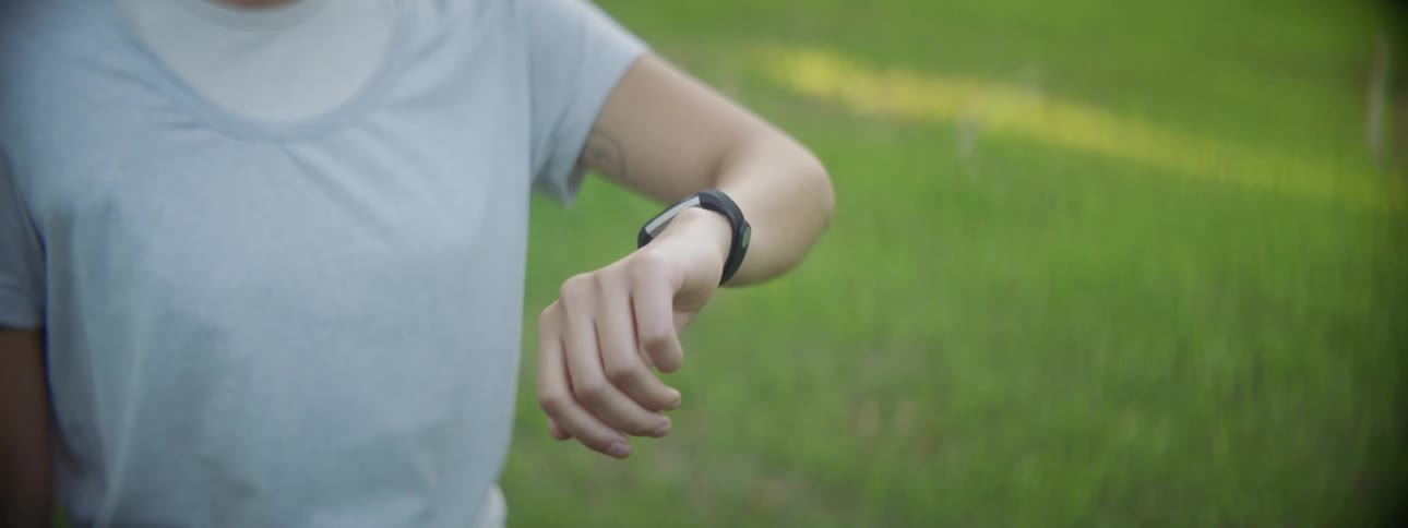 An athletic woman looking at a smart watch in the park
