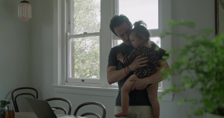 A father is holding his daughter indoors