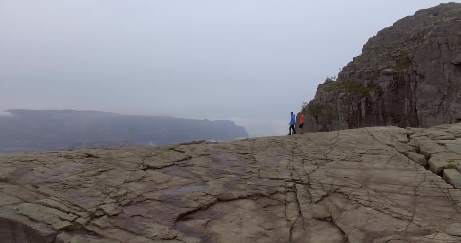 Two people walking towards the edge of a cliff