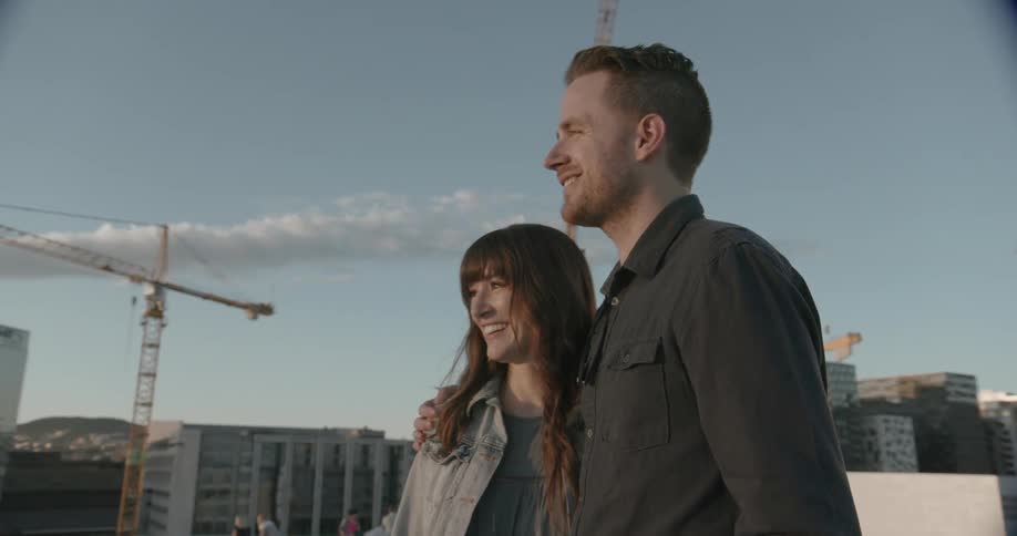 A man has his arms around a woman as they take in a view from a rooftop