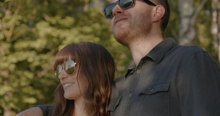 A man has his arm around a women as they talk and look forward