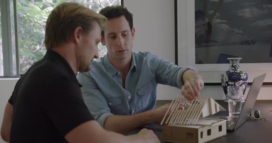 Architect holding a real life scale balsa wood model of a house