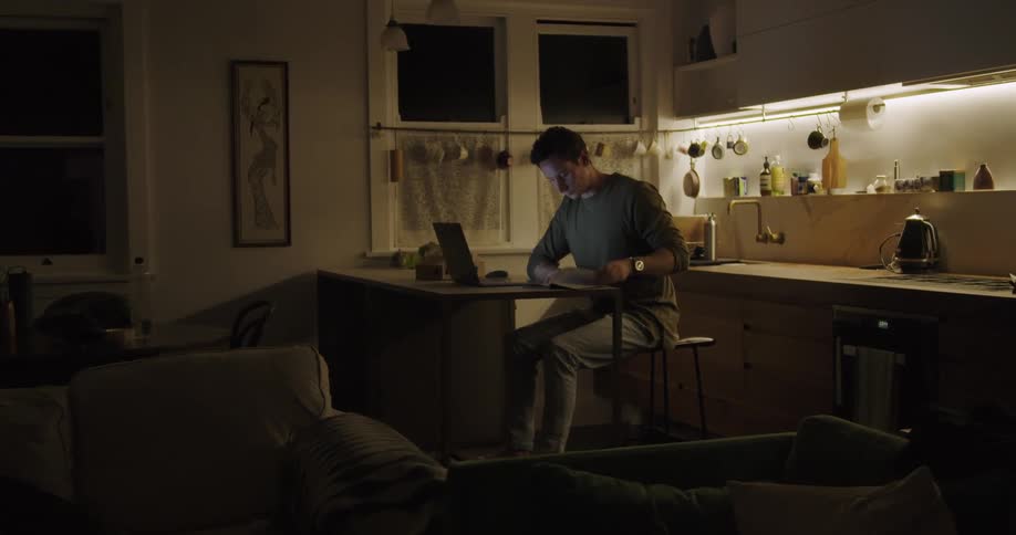 A man is typing on his laptop in the kitchen