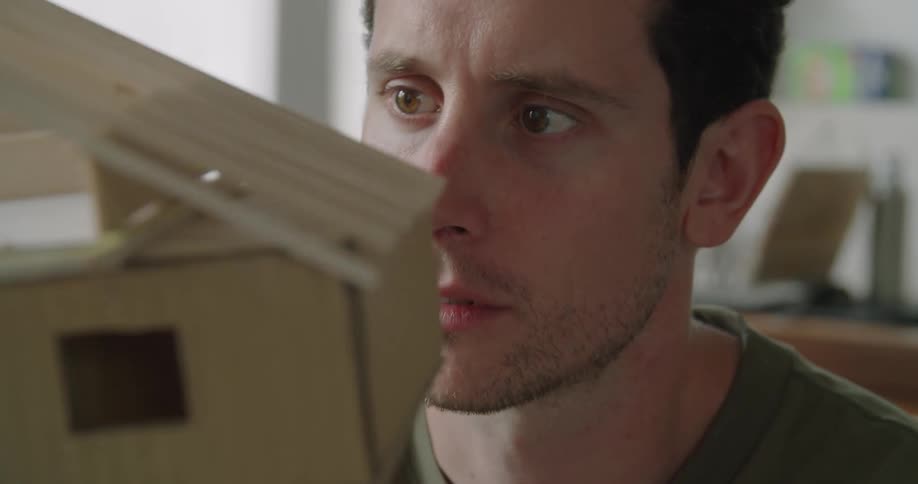 A man is examining a model of a house