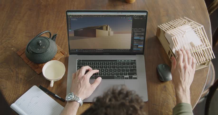 Architect drawing a computer model of a house based on a real life balsa wood scale model