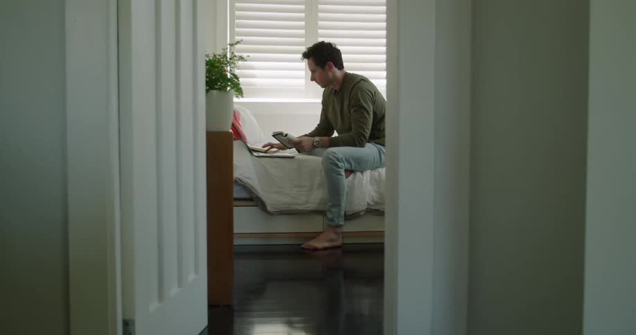 A man is sitting in his room during the day
