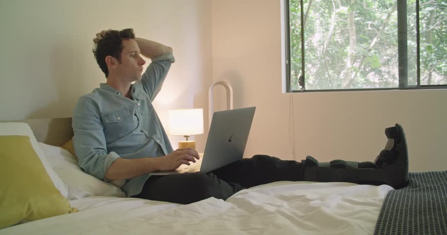 A man is using his laptop in bed