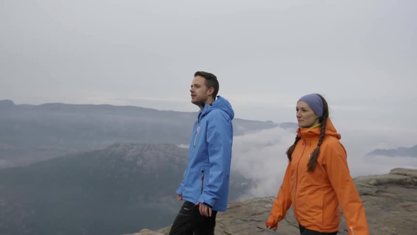 A man and women walk over to the edge of a cliff