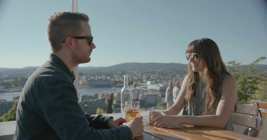 A man and woman have drinks sitting outside at a table