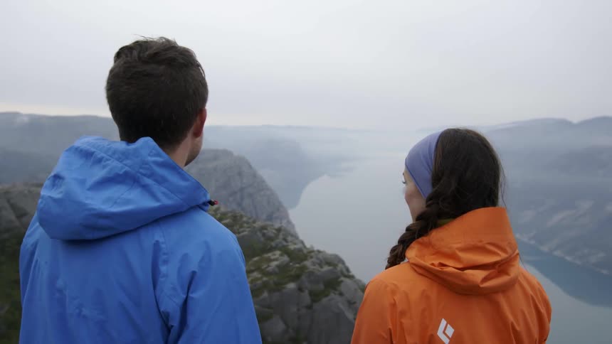 A man and women talk and take in the view from the top of a mountain