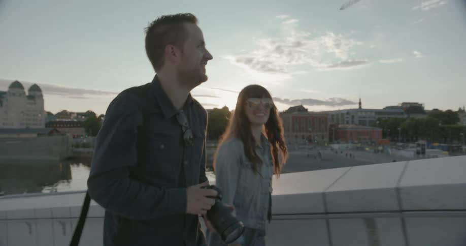 A man and woman are walking uphill near a city