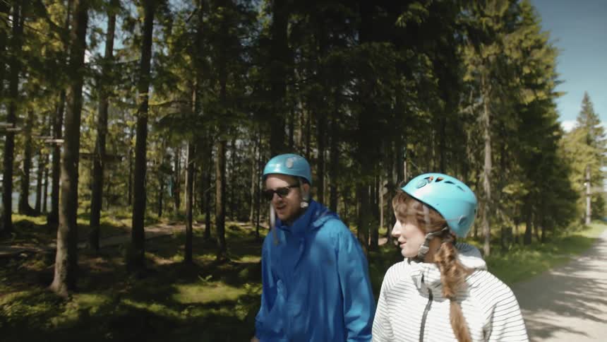 Man and woman wearing helmets walking down a dirt road