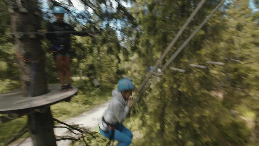 A woman swings from a rope through a forest