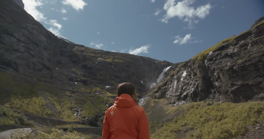 A woman looks up towards a mountain ridge