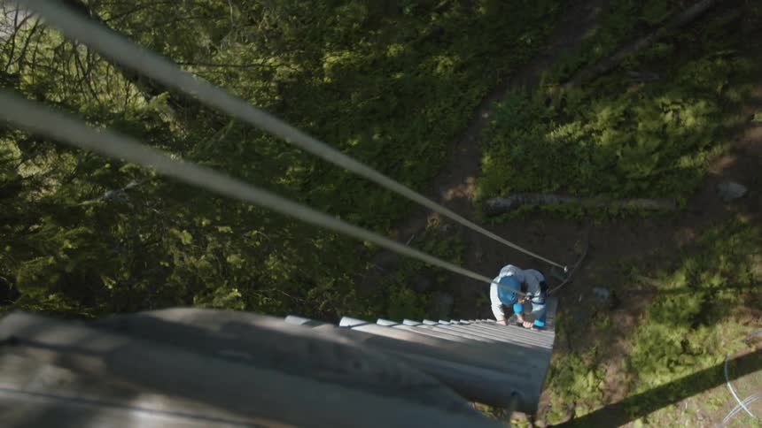A person climbs down a wood and rope ladder