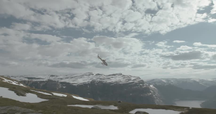 A helicopter flies over snowy and ponds