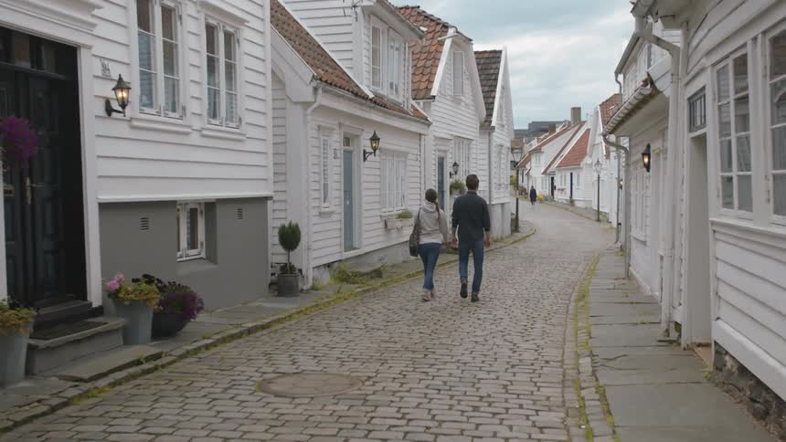 A man and woman walk down a brick sidewalk in a town