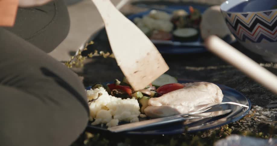 A person scoops food onto a plate