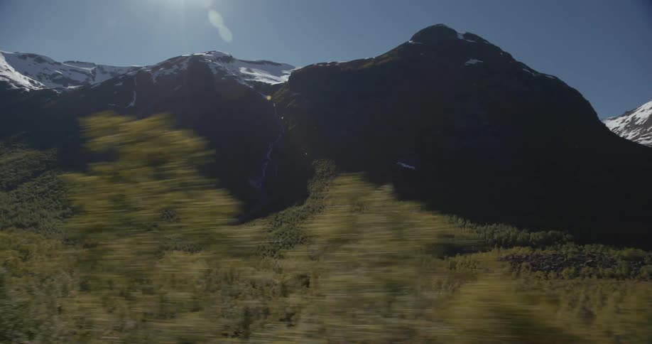 The sun shines over a mountain and trees