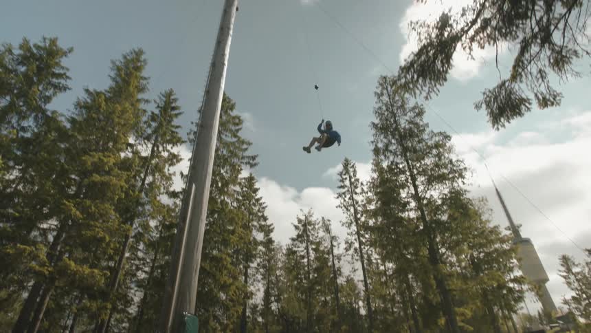 A person descends from a platform using cords