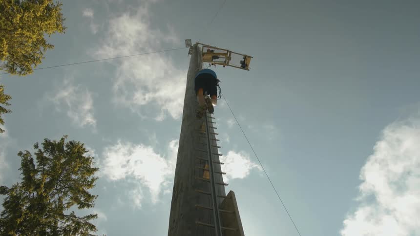 A man is climbing up a pole to a platform